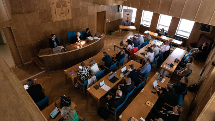 Valtuuston kokous, jossa valtuutetut istuvat omilla paikoillaan salissa. Kuva ylhäältä lehteriltä.