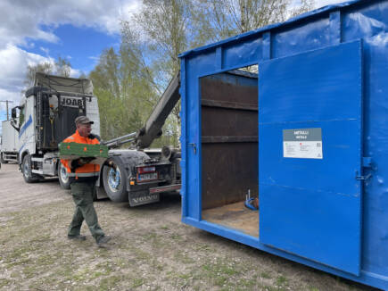 Romulus-bilen samlar in metallskrot och en man bär metallskro till bilen.