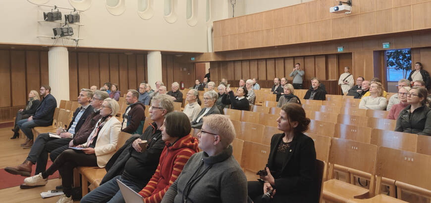 Ihmisiä kaupungintalon juhlasalissa kuuntelemassa infotilaisuutta